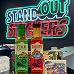 Bottles of Hank Sauce with the StandOut Stickers neon sign